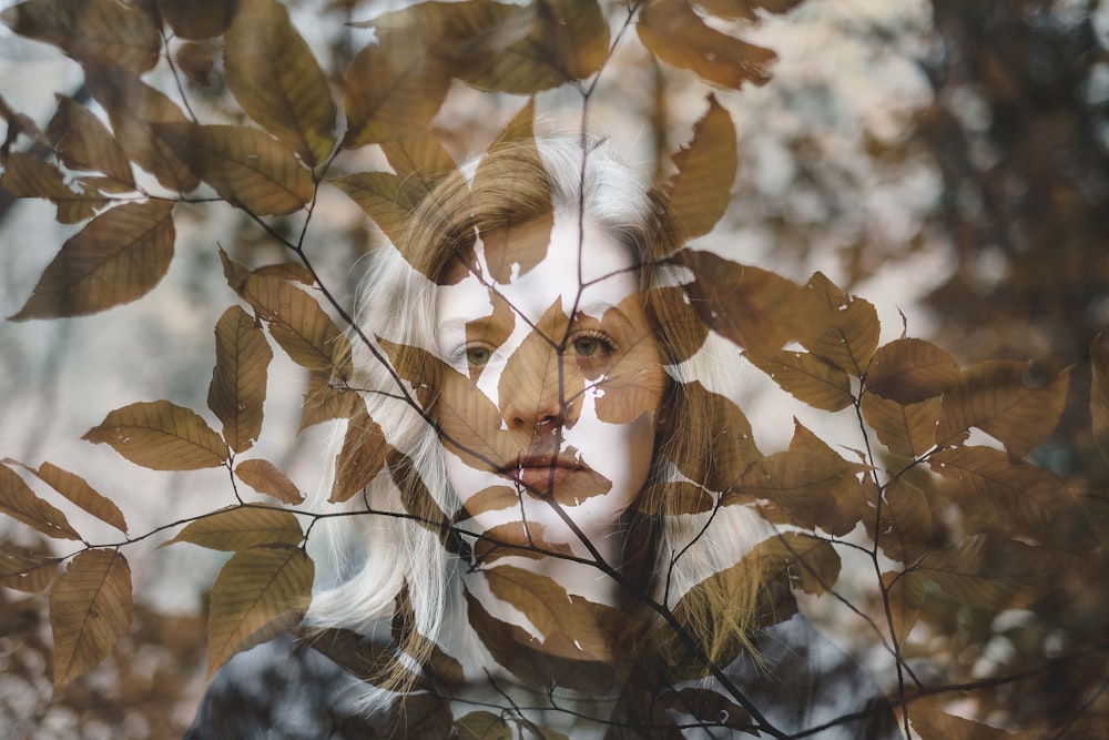 woman behind brown leaves