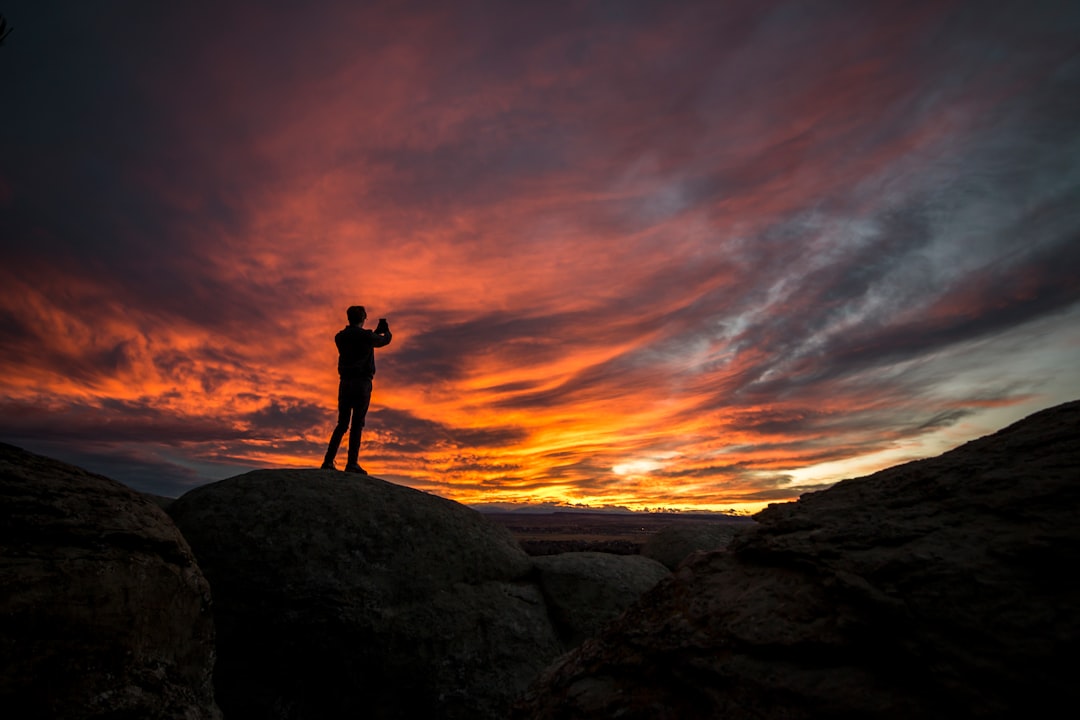 man standing on rocks under cloudy sky