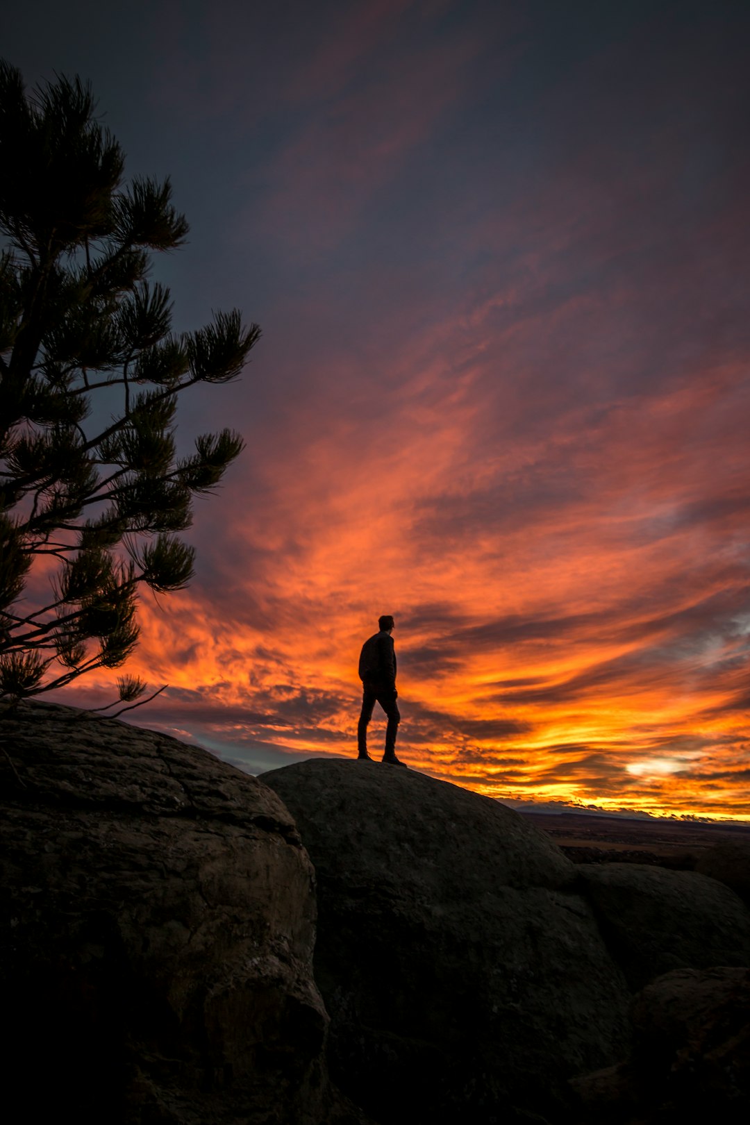 time lapse photography of person standing on cliff silhouette under golden hour