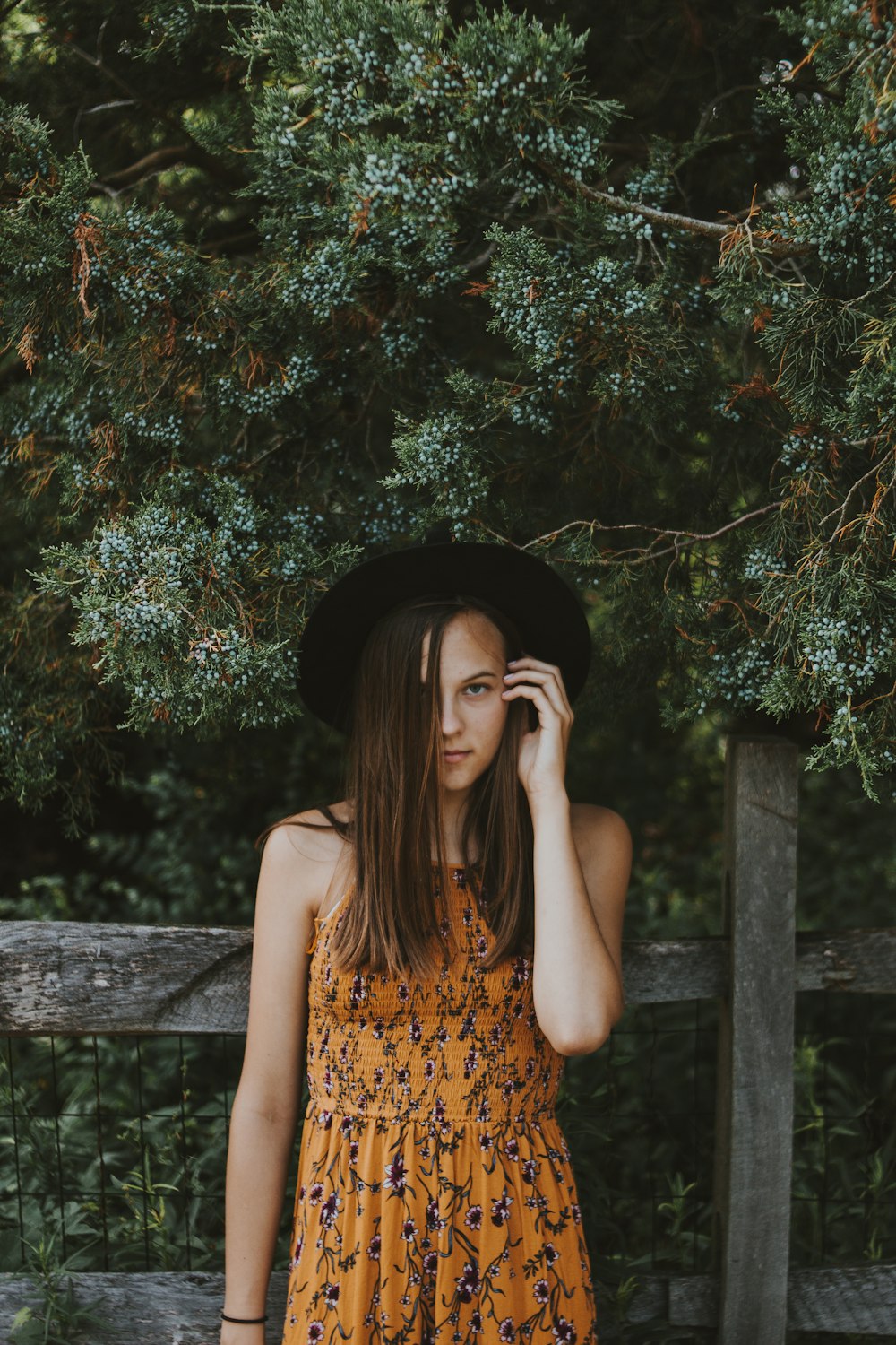 mulher em pé na frente da cerca de madeira marrom durante o dia