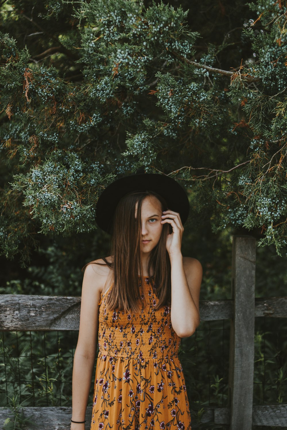 woman standing in front of brown wooden fence during daytime