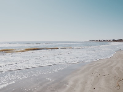 A serene view of the beach just steps away from the home, with gentle waves lapping the shore.