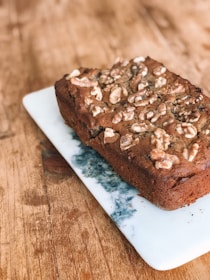 Close-up of a golden banana bread loaf with walnuts on a rustic wooden board.