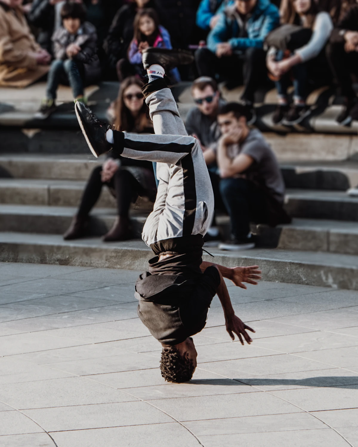 A street performer balances upside down as a crowd watches