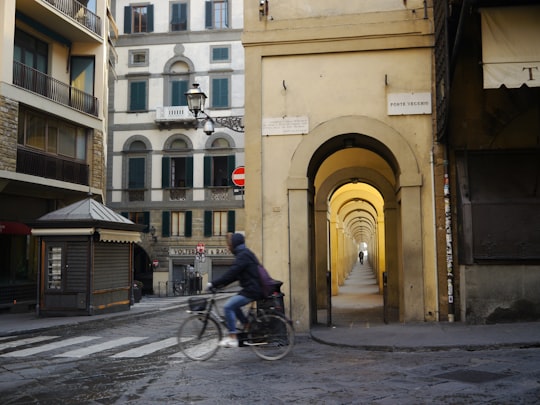 person in black coat riding on cruiser bike near buildings at d aytime in Uffizi Gallery Italy