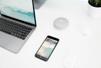 Minimalist workspace featuring a sleek laptop, smart speaker, and clean white surfaces with subtle blue accents reflecting hometechwise style.