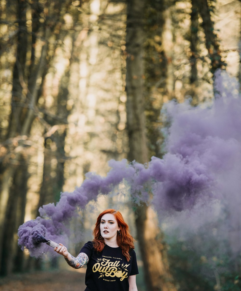 woman holding purple smoke bomb at daytime