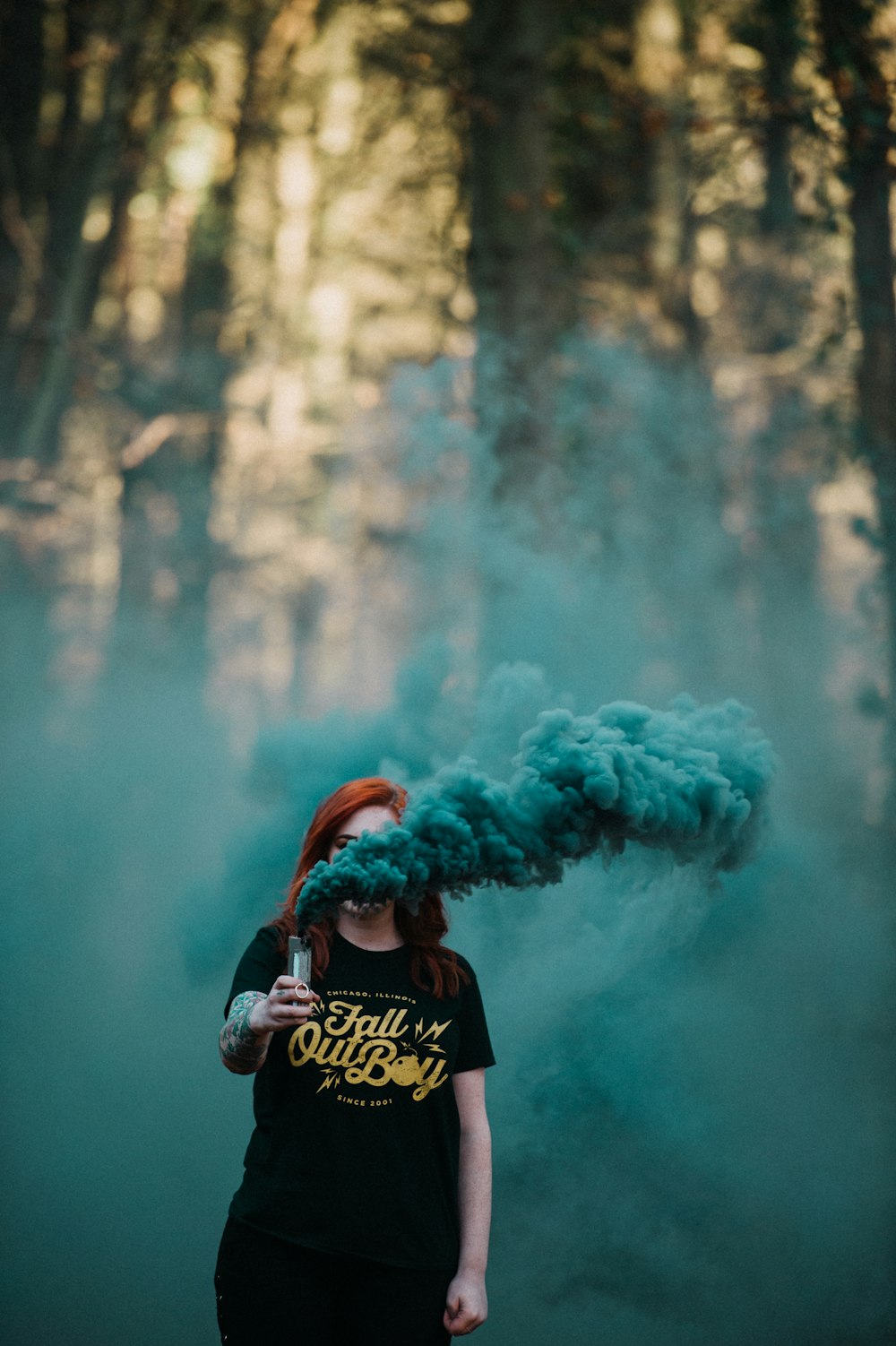 Frau mit Vaporizer setzt blauen Rauch in der Nähe eines Waldes frei
