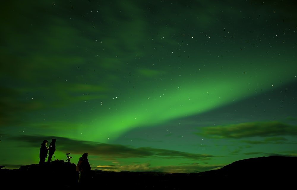 silhouette of three persons watching the phenomenon sky