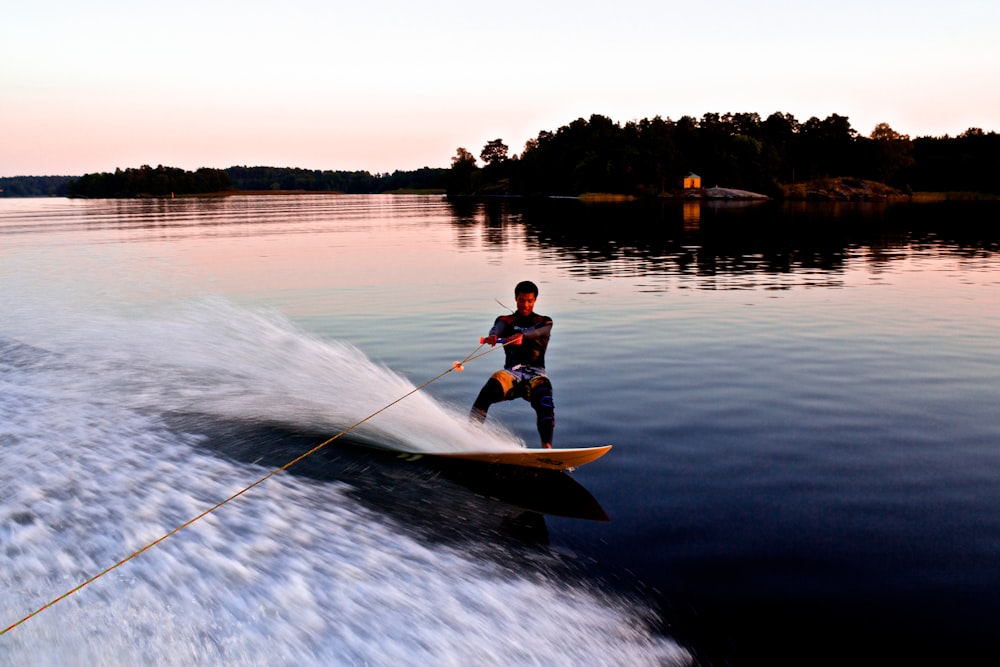 man riding yellow wakeboard on body of water