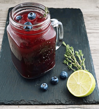 clear glass mason jar with red liquid and lemon beside