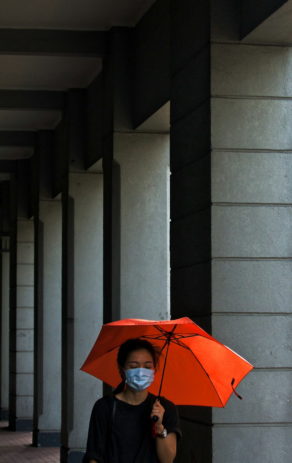 women's holding umbrella beside post