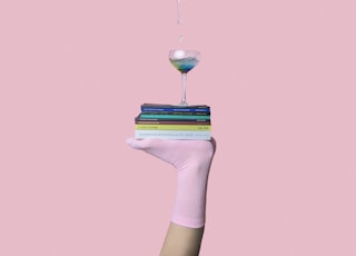 person balancing martini glass above book with feet