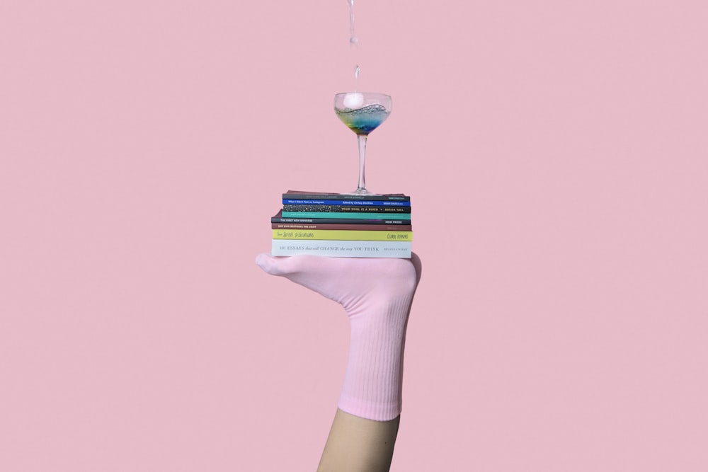 person balancing martini glass above book with feet