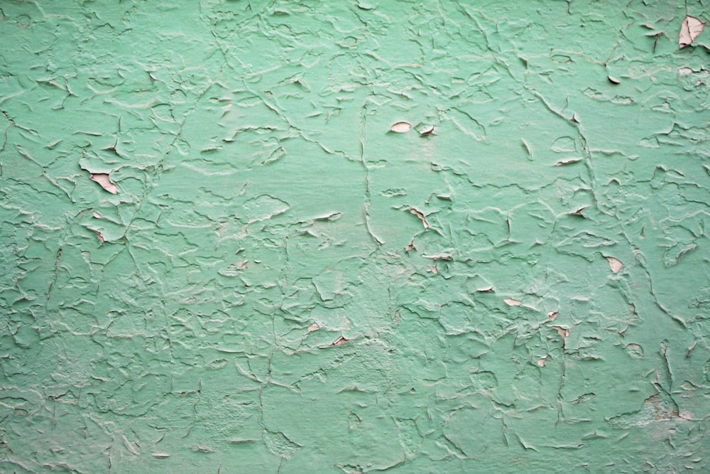 eine grüne Wand mit abblätternder Farbe darauf