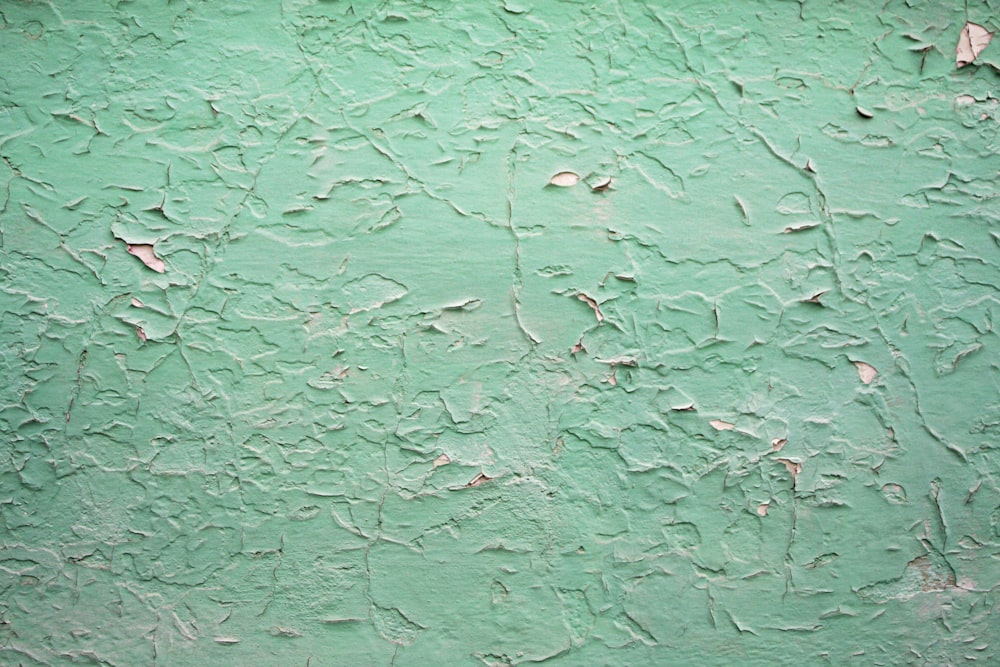 una pared verde con pintura descascarada