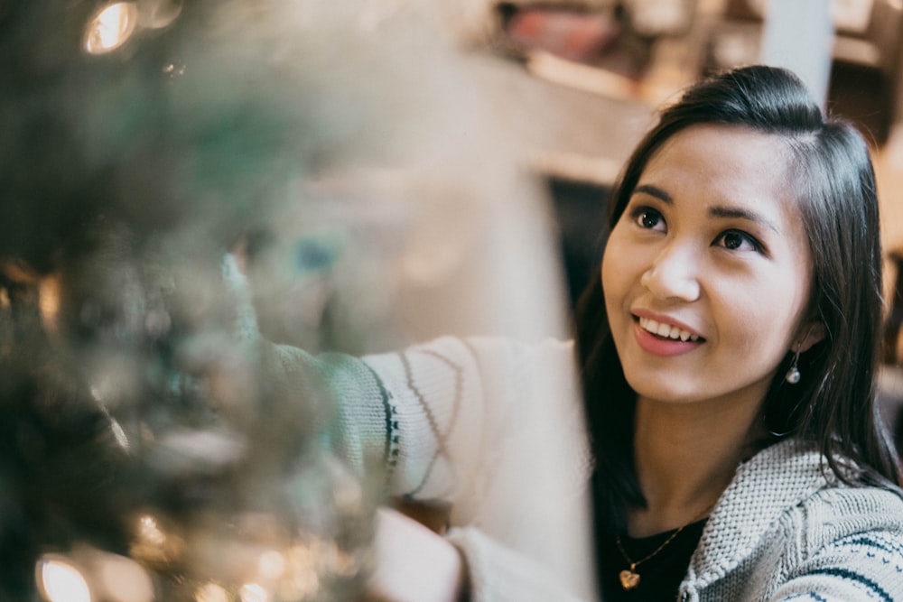 woman smiling while decorating at Christmas tree