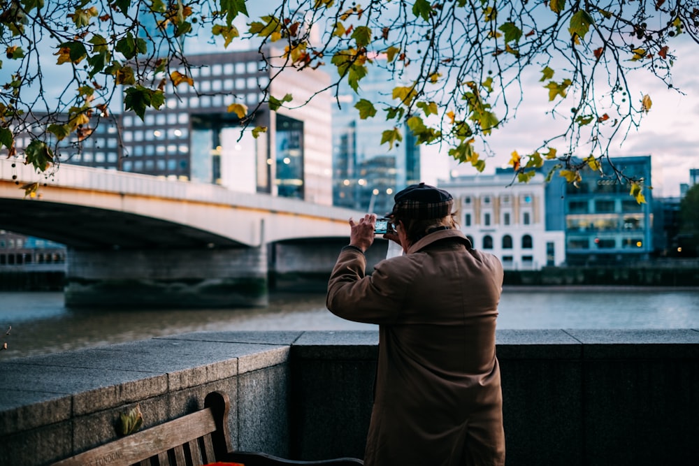 man standing beside river near concrete bridge