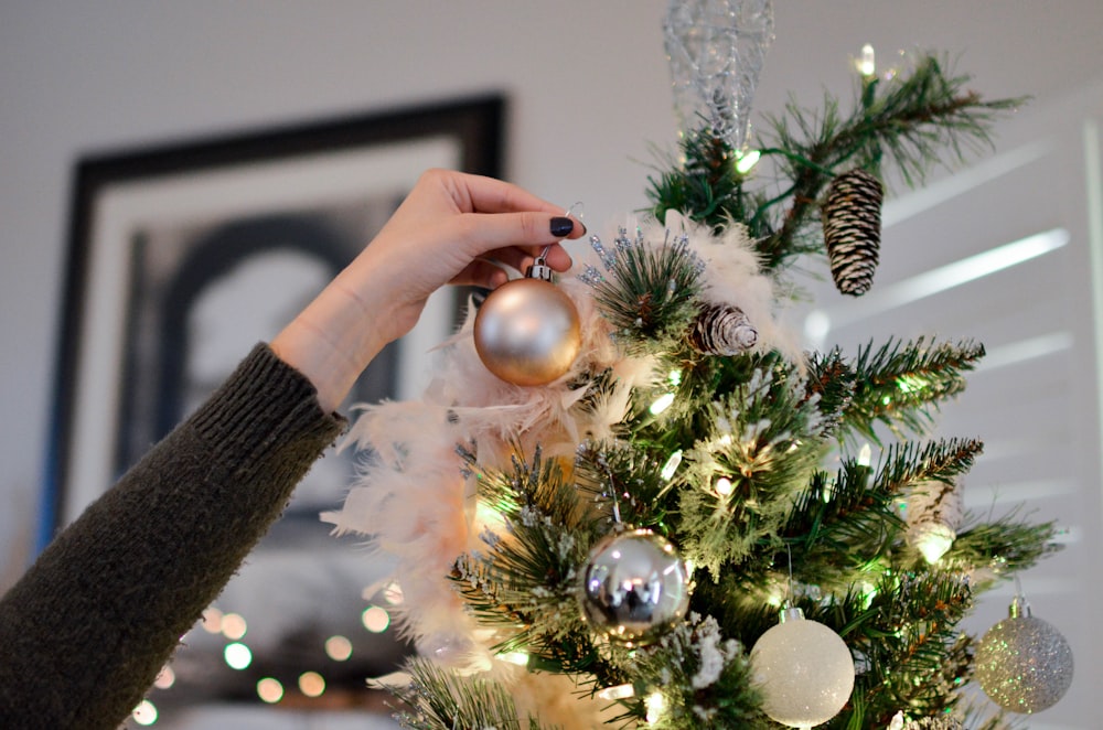 persona colocando una chuchería en la parte superior del árbol de Navidad