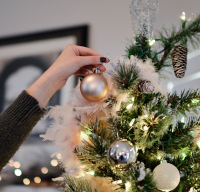 person putting bauble on top of Christmas tree