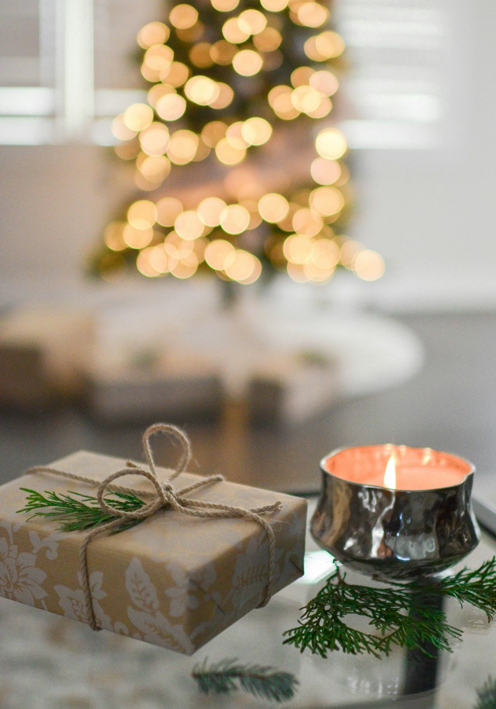 Caja de regalo marrón junto a vela votiva de acero inoxidable
