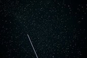 A night sky filled with constellations and a sleek satellite passing by.