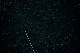 A night sky filled with constellations and a sleek satellite passing by.