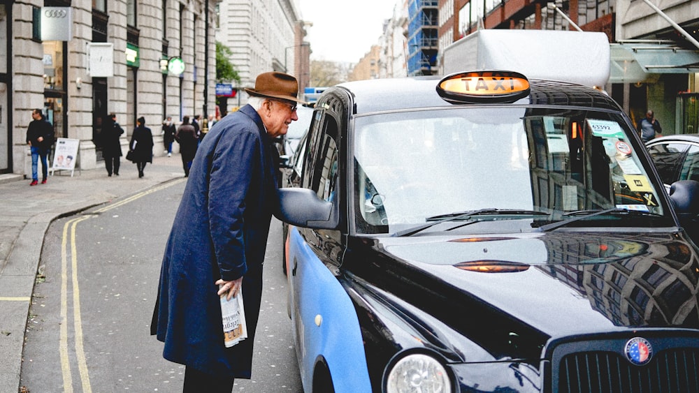 man talking through taxi car mirror during daytime