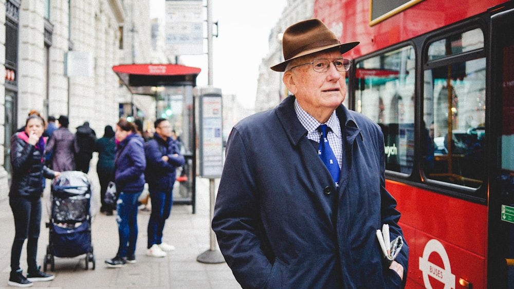 man standing near red bus at daytime