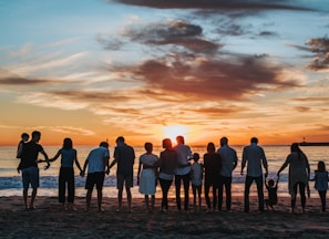 people standing on shore during golden hour