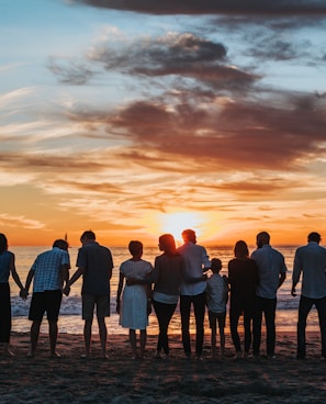 people standing on shore during golden hour