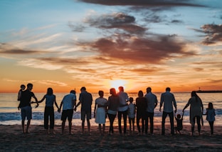 people standing on shore during golden hour