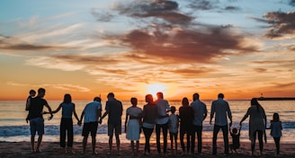 people standing on shore during golden hour