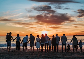 people standing on shore during golden hour