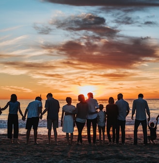 people standing on shore during golden hour