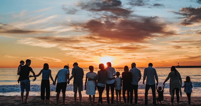 people standing on shore during golden hour