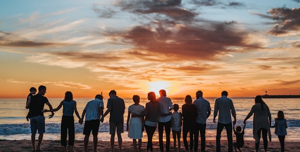 people standing on shore during golden hour