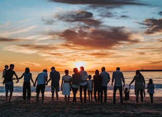 people standing on shore during golden hour