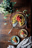 A rustic wooden table set with a hearty vegetable and herb tart freshly baked in the country kitchen.