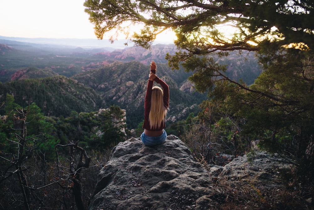 Mujer sentada en roca gris observando la naturaleza