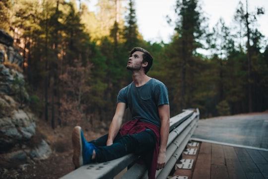 man sitting on rails looking up during daytime in Flagstaff United States