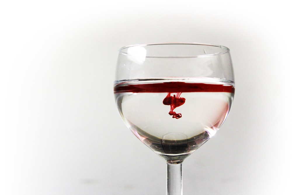 verre à vin transparent rempli d’un liquide rouge