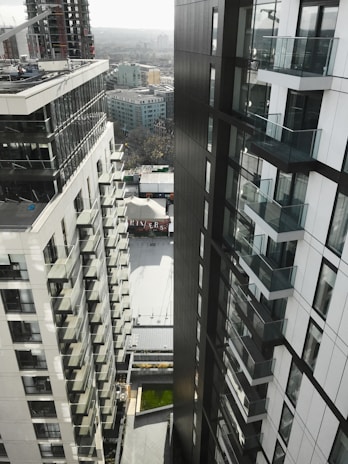 Close-up of a sleek glass balcony frame with a city view in the background.