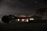 A nighttime shot of a house with newly installed windows glowing warmly inside.