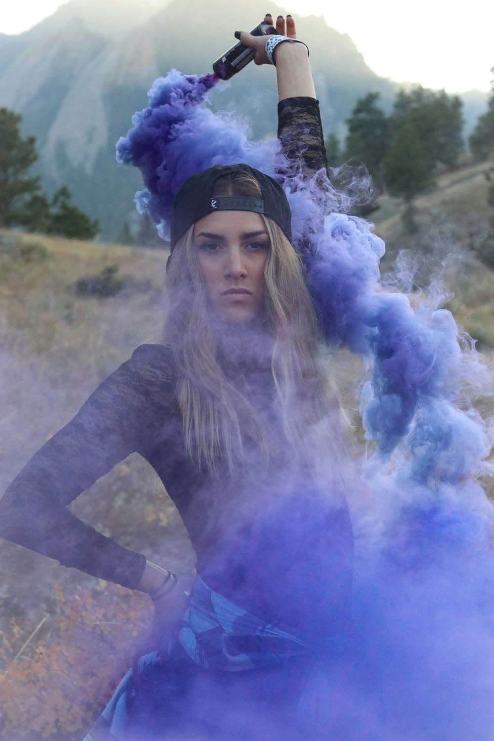 woman raising purple smoke bomb during daytime