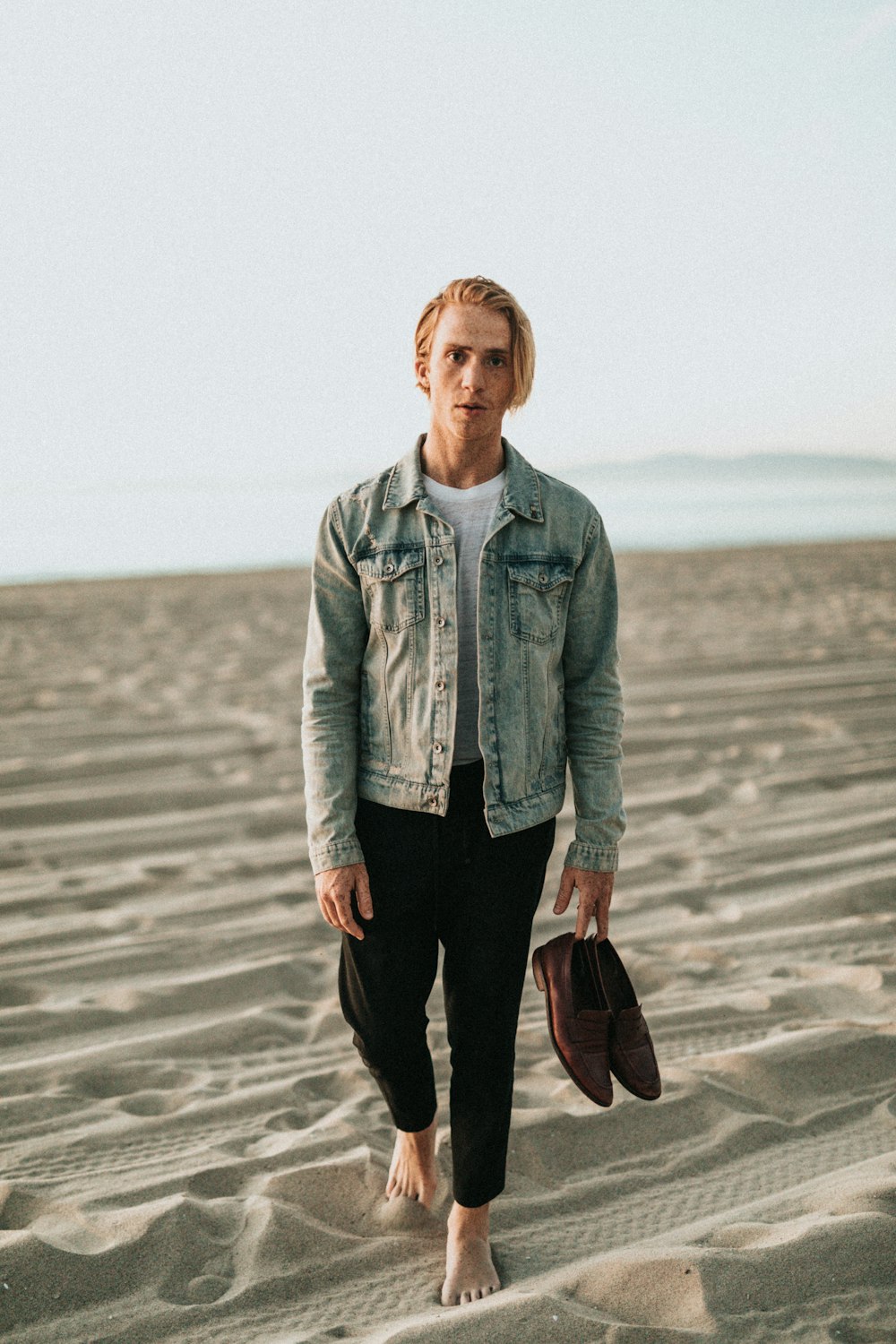 man walking on white sand near beach