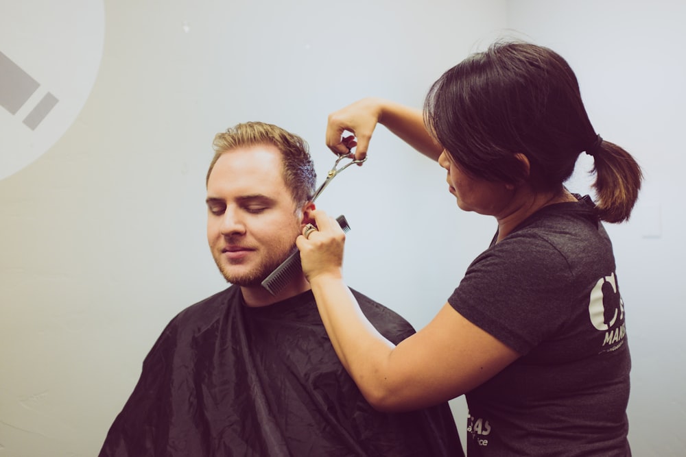 woman trimming the hair of a man