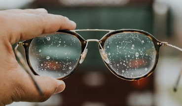 a hand holding a pair of glasses with water droplets on it