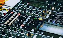 A close-up of a DJ mixing tracks on a sleek console with black and silver accents.