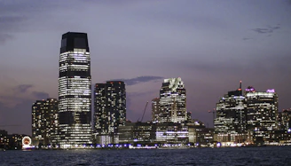 High-resolution photo of a modern city skyline with glowing lights against a twilight sky.